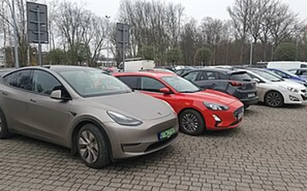 Samochody osobowe na parkingu, w tym elektryczny SUV na polskich tablicach