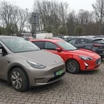 Samochody osobowe na parkingu, w tym elektryczny SUV na polskich tablicach
